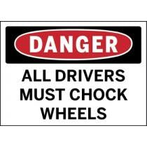 Safety sign warning drivers to chock wheels with a red border and black text.