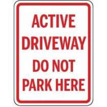 Sign indicating 'Active Driveway Do Not Park Here' with red text on a white background