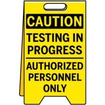 Yellow caution sign with black text 'Testing in progress, authorized personnel only' on a white background