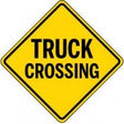 Yellow diamond-shaped traffic sign with 'TRUCK CROSSING' text on a white background
