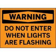 Warning sign with text 'WARNING DO NOT ENTER WHEN LIGHTS ARE FLASHING' on an orange background