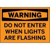 Warning sign with text 'WARNING DO NOT ENTER WHEN LIGHTS ARE FLASHING' on an orange background